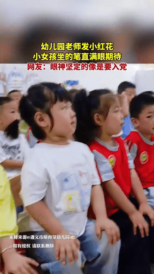 幼儿园教室里，老师准备给小朋友发小红花。
前排这个小女孩，坐得腰背笔直，眼睛紧紧
