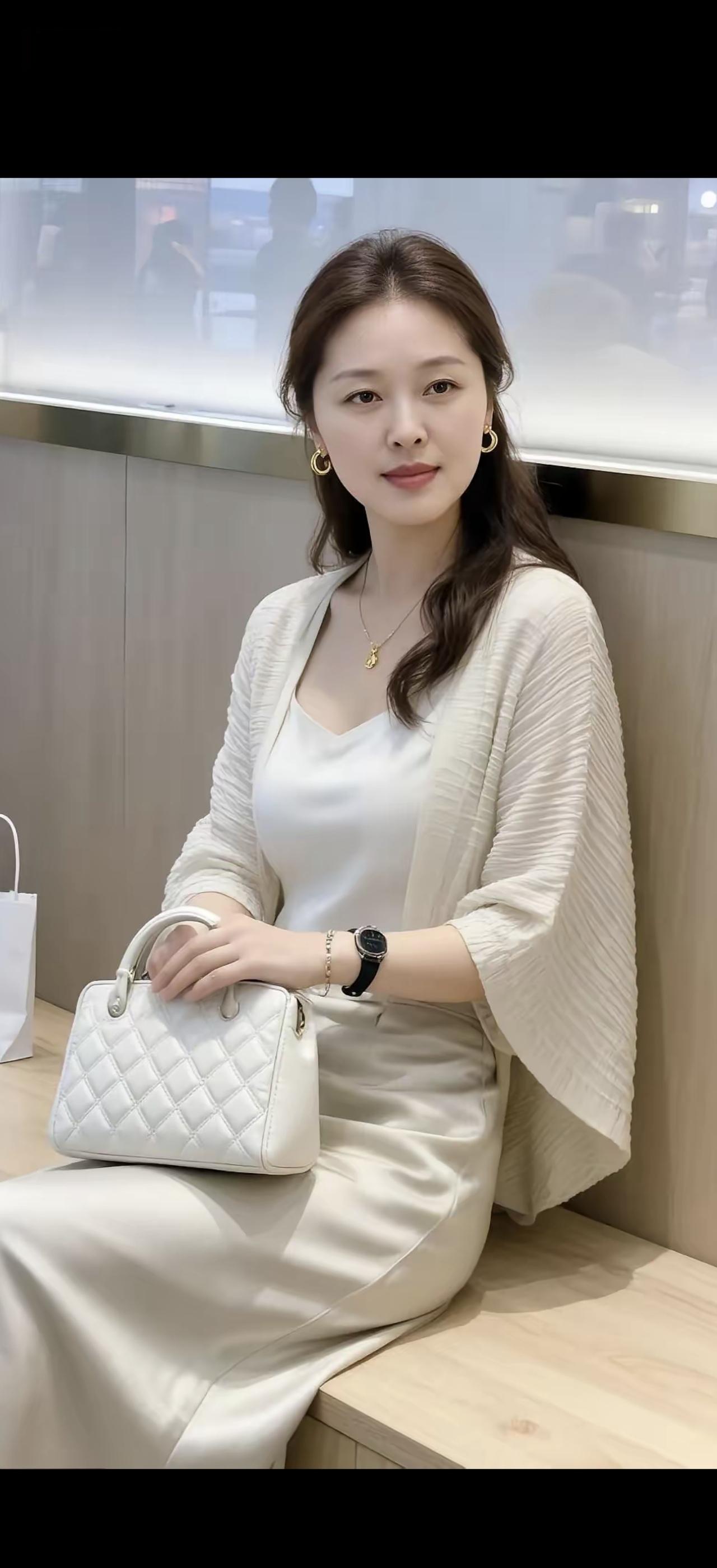 她穿着白色连衣裙，手拿小包。