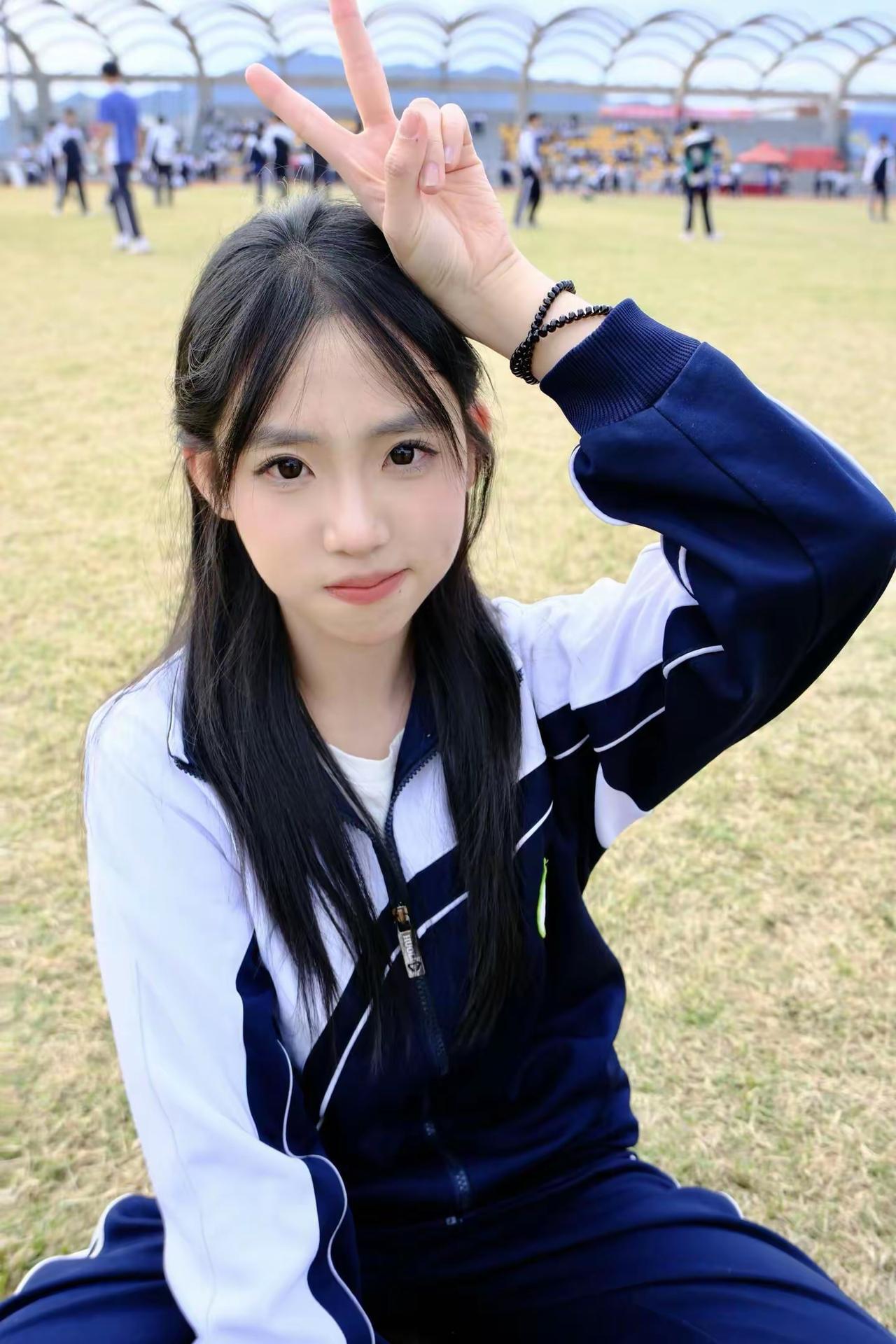 女孩在草地上比出V字手势。比心自拍