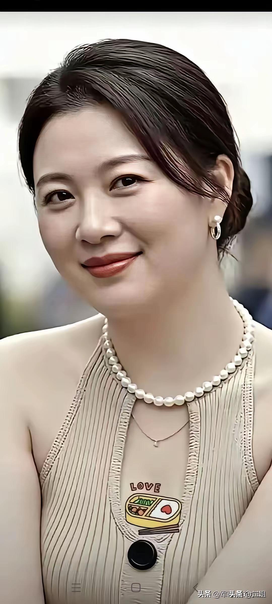 这位女士戴着珍珠项链，面带微笑。