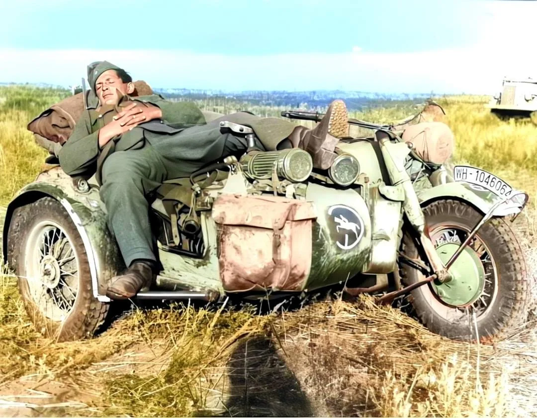 1942年，俄罗斯南部，德国第24装甲师的一名士兵睡在宝马R75摩托车...