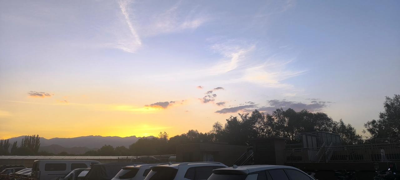贺兰山落日收官。
夕阳坠入山峦，晚霞铺满天际，一半金光，一半浅蓝。
山野藏暮色，