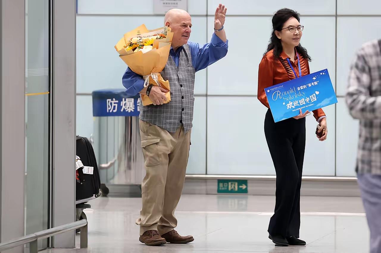8月23日，鄂尔多斯机场的电动扶梯上，69岁的美国老人捧着鲜花缓缓下行，对面69