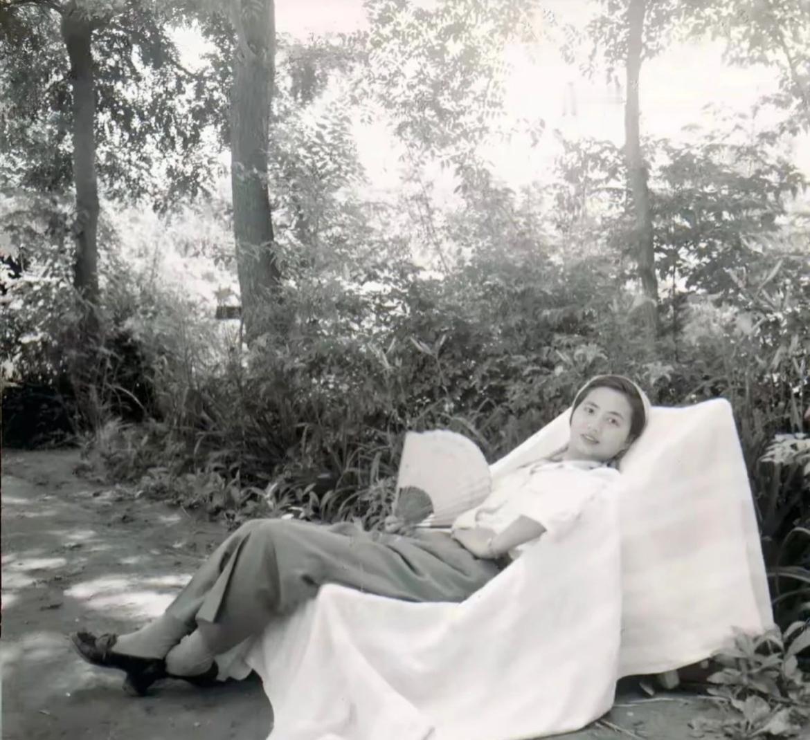 1956年，陈毅元帅夫人张茜手拿扇子，斜躺在树下椅子上休憩的老照片，阳光透过树叶