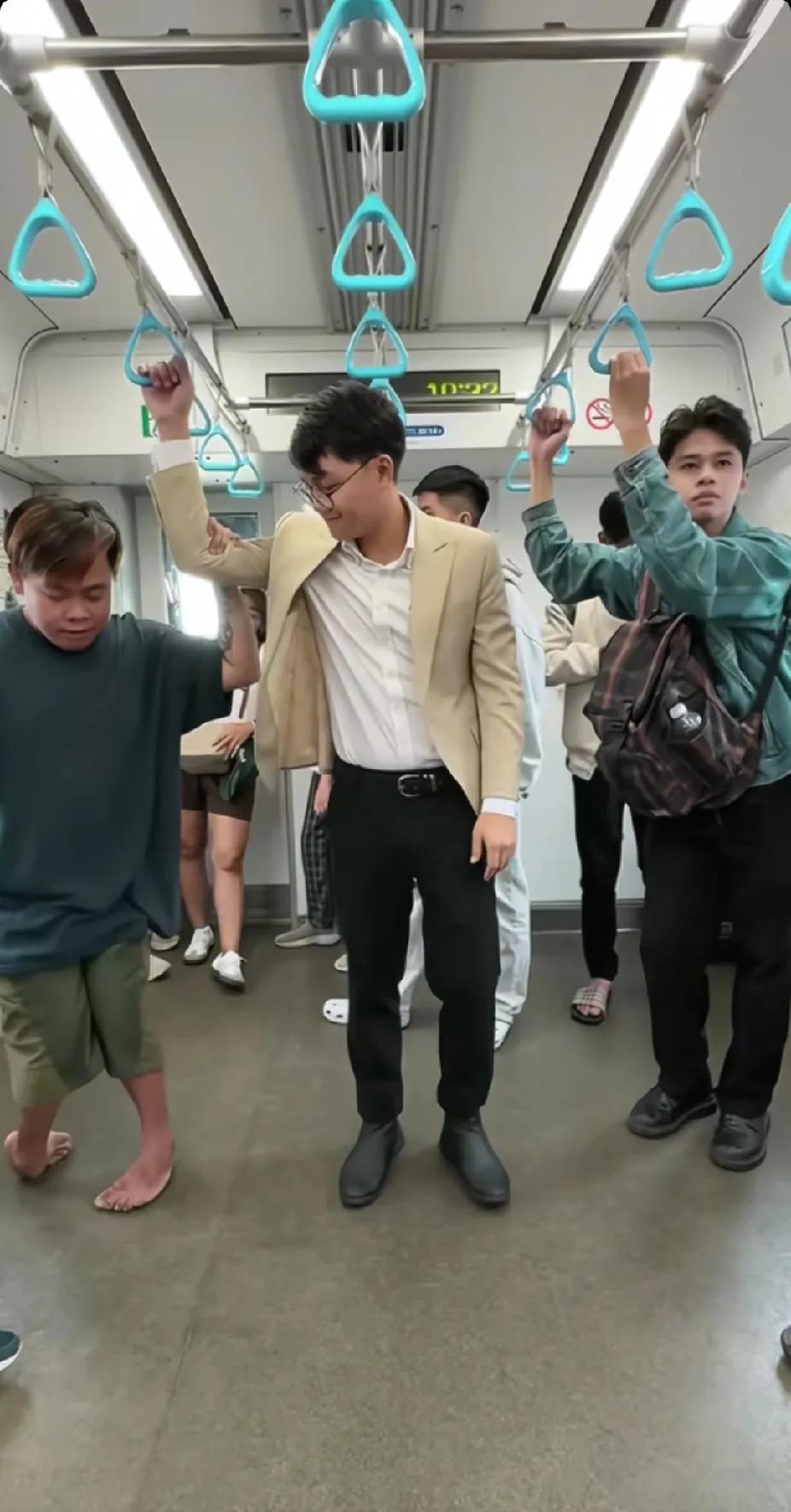 地铁上，残疾小伙子有些费劲地拉着吊环，站在旁边的陌生男子看了看后，突然伸出了一只