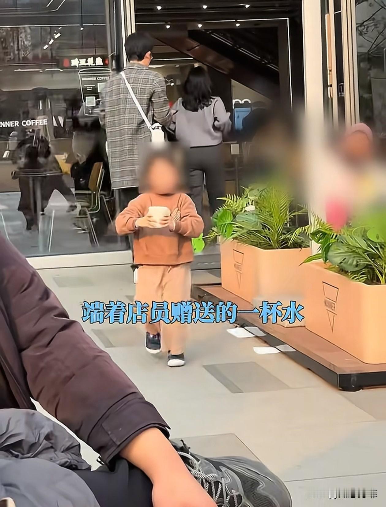 浙江，一小女孩端着店家赠送的水，小心翼翼地走向妈妈，结果被旁边路过的陌生女孩故意