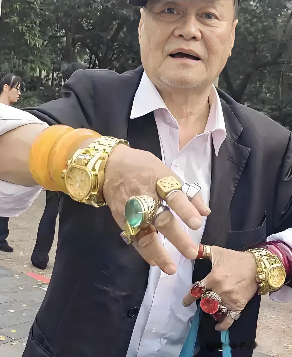 柳州有一炫富老人戴两个金表，十个手指均带上金戒指，每天在公园转悠，或睡或站，无不