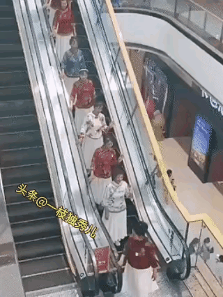 这些中年大妈穿着差不多一样的衣服，也不知是在搞什么活动，但是在乘坐公共电梯时，她