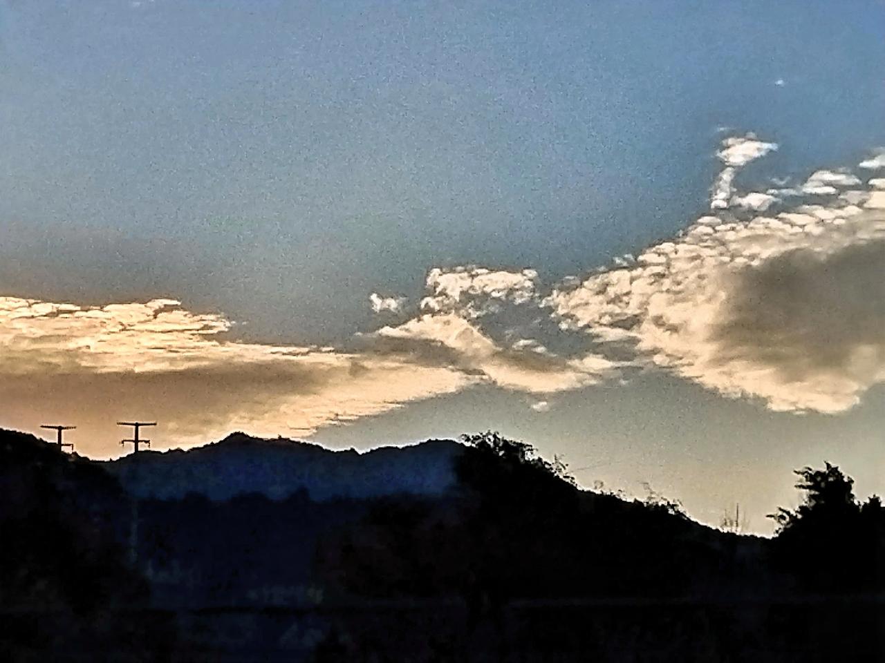 夕阳西下，云海翻滚，远山如黛，静谧而美丽。金色的余晖洒在翻滚的云海上，像是给云朵