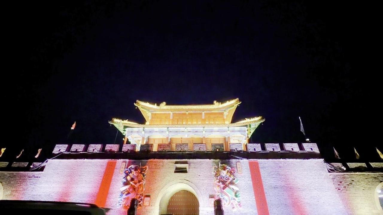 暮色里的古城火锅城，院门一开竟藏着半条街的热闹。几十张桌子沿着街道铺开，红汤咕嘟