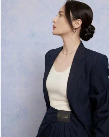 蒋勤勤身着深蓝色细条纹西装外套，线条流畅，剪裁得体，凸显出干练的气质。内搭白色针