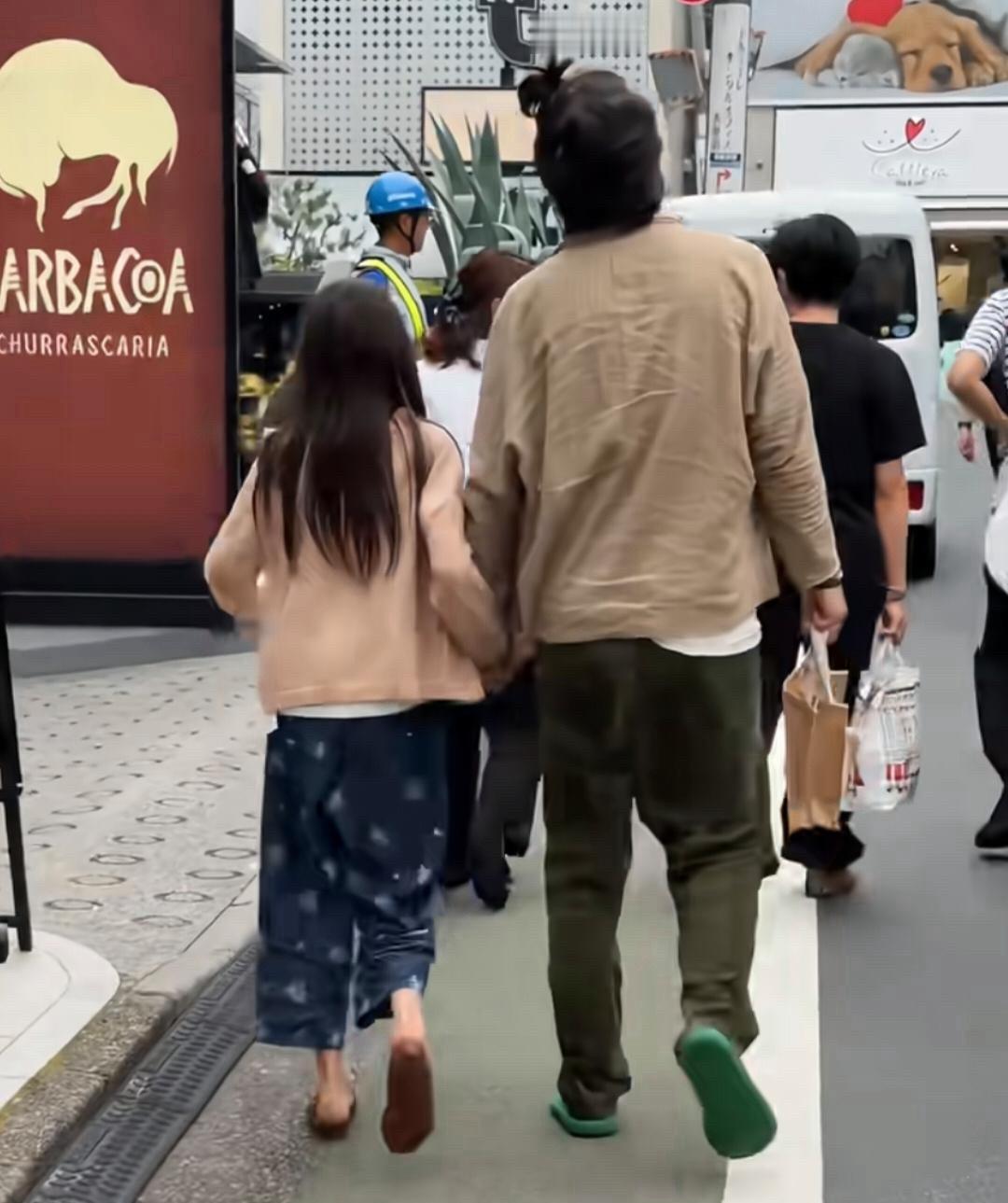 45岁陈冠希和9岁女儿在日本东京牵手逛街被偶遇，他的穿衣打扮不修边幅，背影看起来