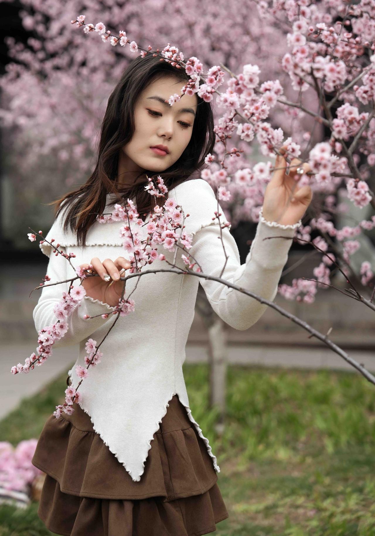 杏花树下，少女轻抚花枝，春意盎然。