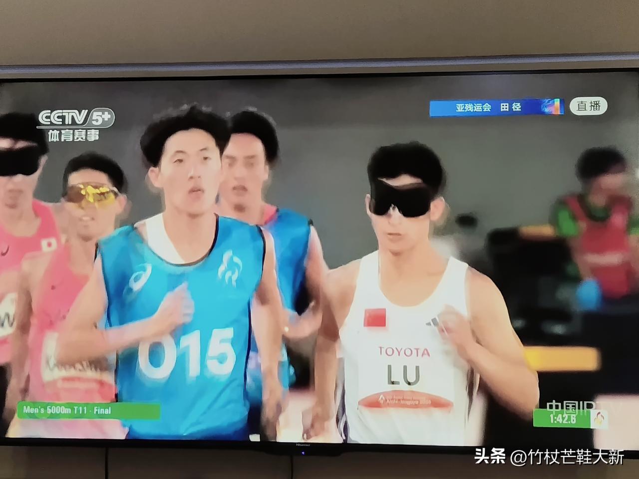 亚残运会上5000米比赛，一位运动员旁边有一位引导员，他们之间有一根带子系在各自