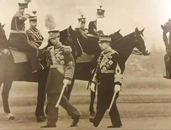 照片中身着军装的两人，左侧是伪满洲国皇帝溥仪，右侧是日本天皇裕仁。
​
1935