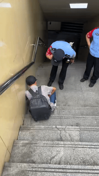 网友在地下通道入口处发现一名中年男子用手捂着肚子，表情非常痛苦的靠着墙坐在台阶上
