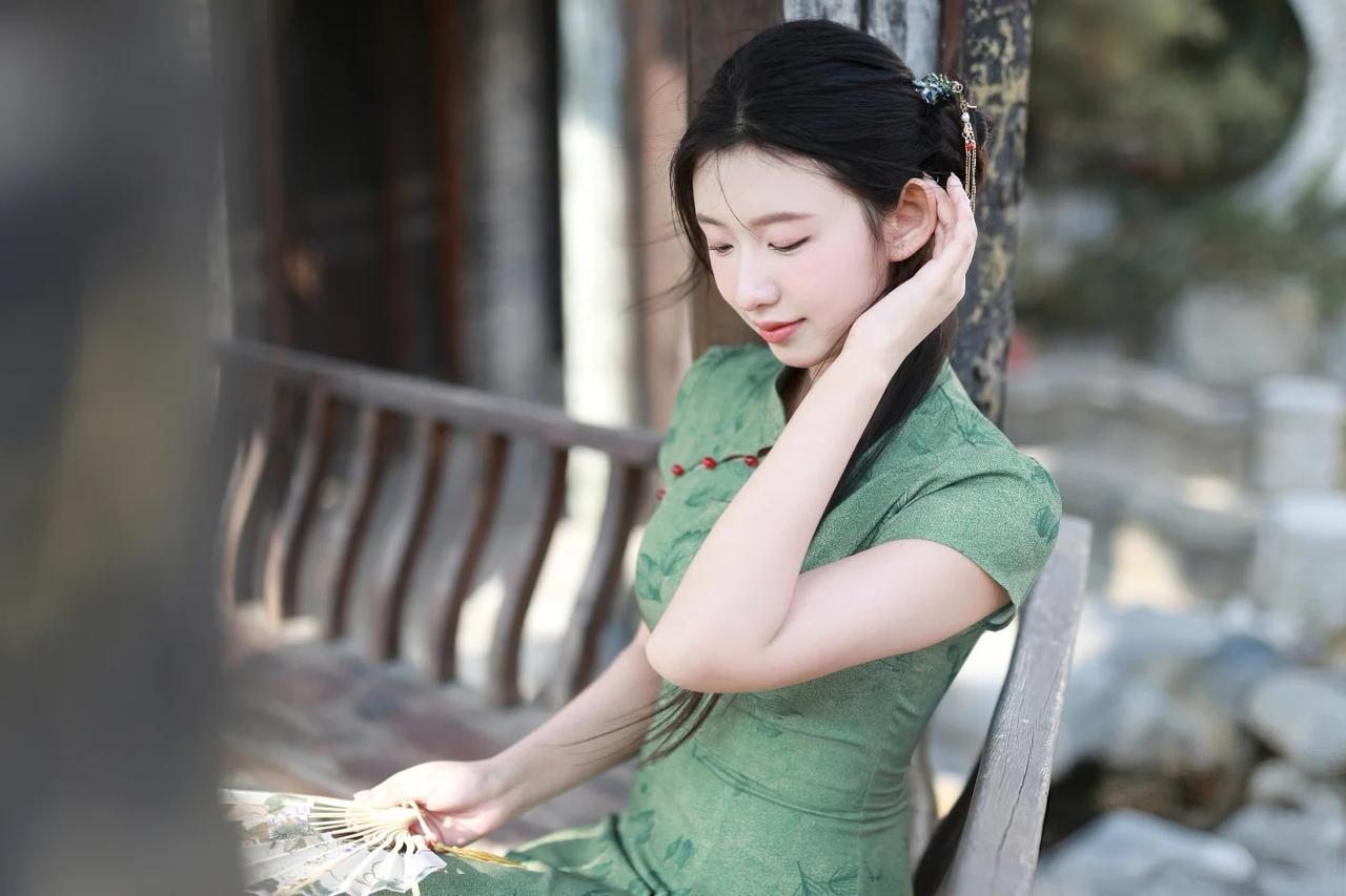 你身着一袭青碧色旗袍，宛若从古画中走出的仙子，衣袂飘摇间尽显东方神韵。那旗袍上暗