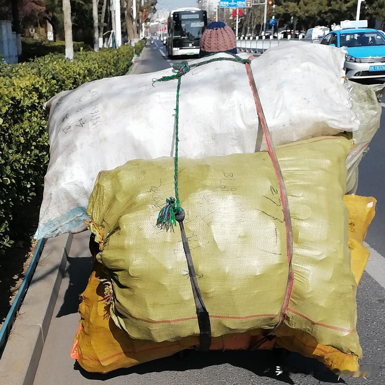 干净宽阔、一尘不染的城市大马路上，依然有人在艰难地跋涉。她拖着一车矿泉水瓶和易拉