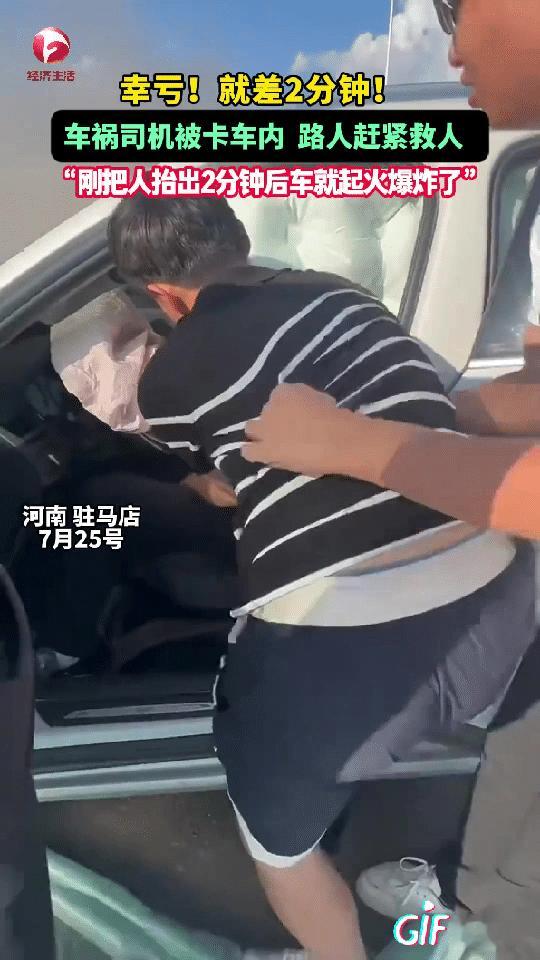 河南驻马店一男子开车行驶在马路上，突然看到路边一辆汽车着火了，他们看到司机被卡在