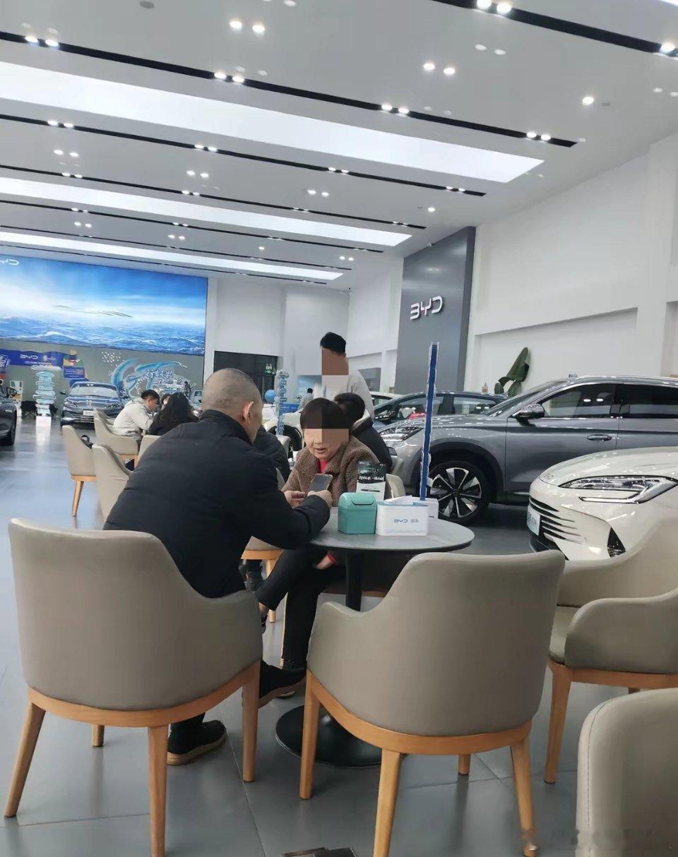 比亚迪 4S 店，即便不是周末，依然人潮涌动，洽谈桌都快坐满了。停车场更是拥挤得