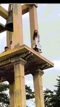 女子在钟台上失足后仰，幸亏一名男子及时抓住了她的一条腿。
可女子不但不配合男子救