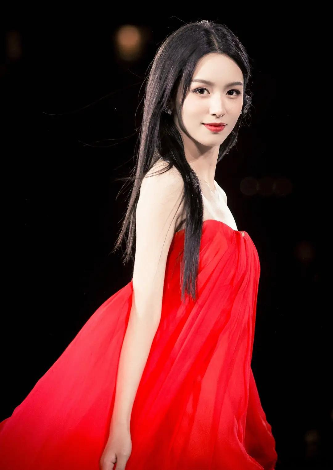 周也亮相巴黎时装周T台走秀，一袭红色抹胸长裙惊艳全场，撩起裙摆的动作自信从容，台