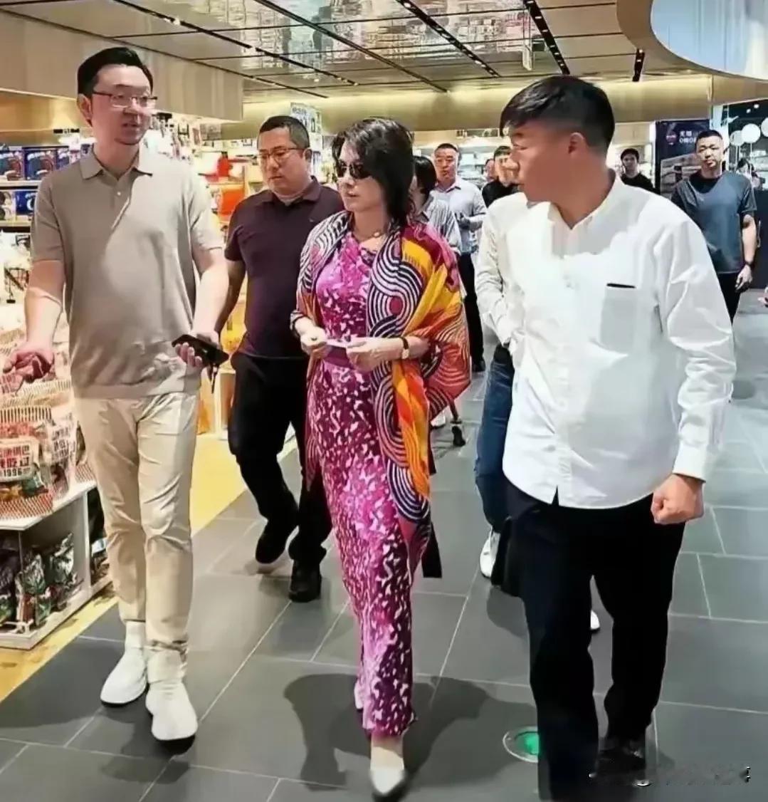这是谁呀，先不说这前呼后拥的架势，都66岁了，还穿这么花哨的裙子，披一条鲜艳的丝