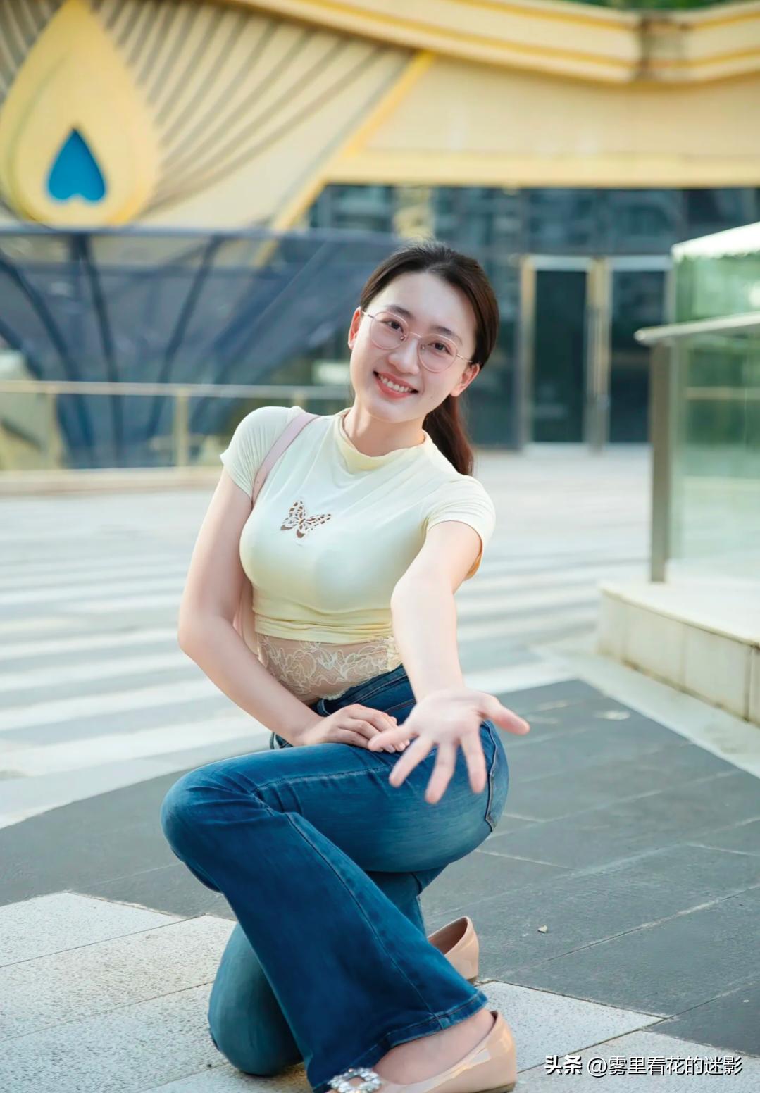 浅黄衫软色初匀，蓝裤轻舒步履融。长发垂肩镜影澈，笑立广场入屏中。