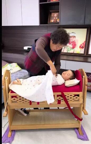 婴儿睡觉，奶奶把婴儿这样绑在床上，看起来是很不错，这样小孩子睡觉有一种被抱紧的感