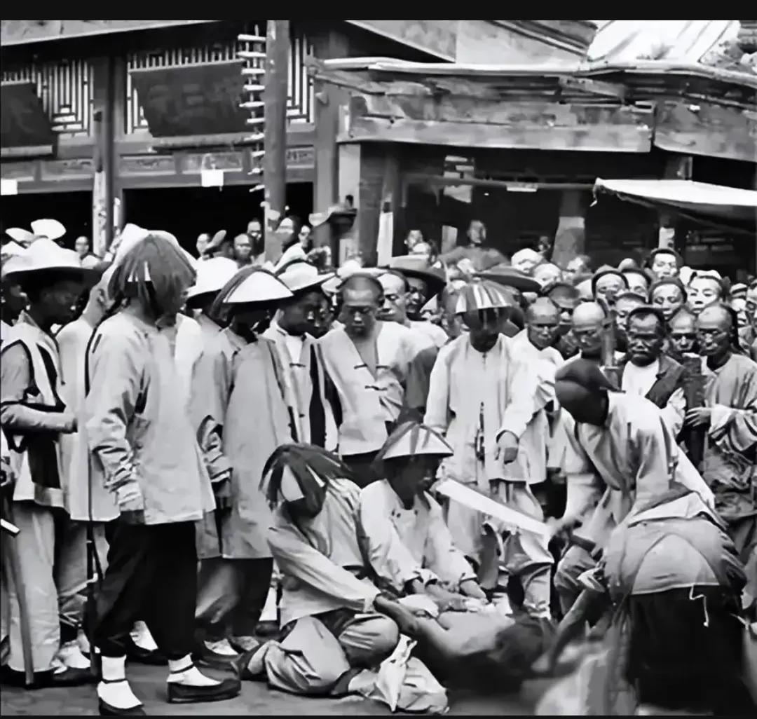 1900年，北京菜市口，一名犯人处决的现场，在镜头中，犯人跪在地上，他看起来非常