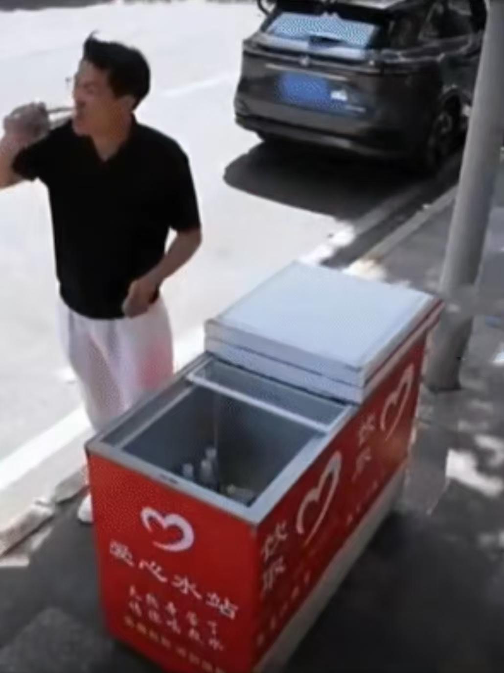 重庆街头的一处爱心冰柜边，一个男子把车停下只拿了一瓶冰水，旁边的人以为他又来白拿
