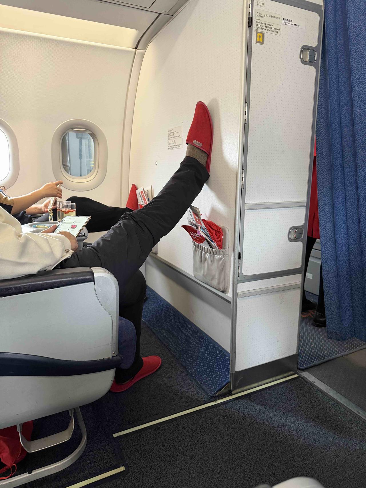 我此刻在飞机上，准备出差。旁边公务舱座位的一位60岁左右大姐的姿势，我确实服气！