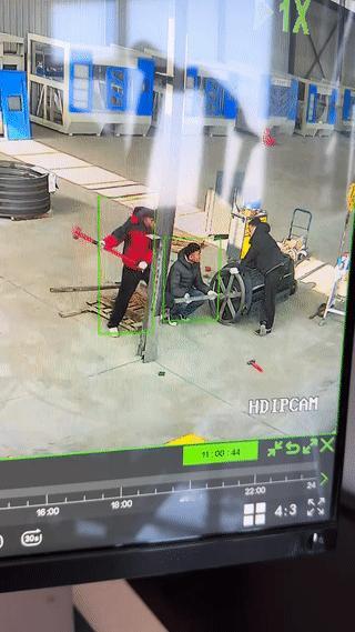 这是监控摄像头记录下的惊险一幕！
工厂车间里有三个人正在干活。
其中有一个穿红棉