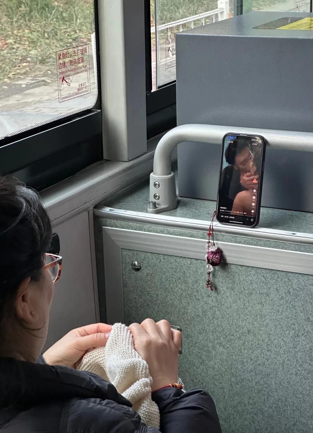 公交车上大妈边织毛衣边看甜宠剧，剧中情侣热吻的画面引得乘客侧目，大妈却气定神闲，