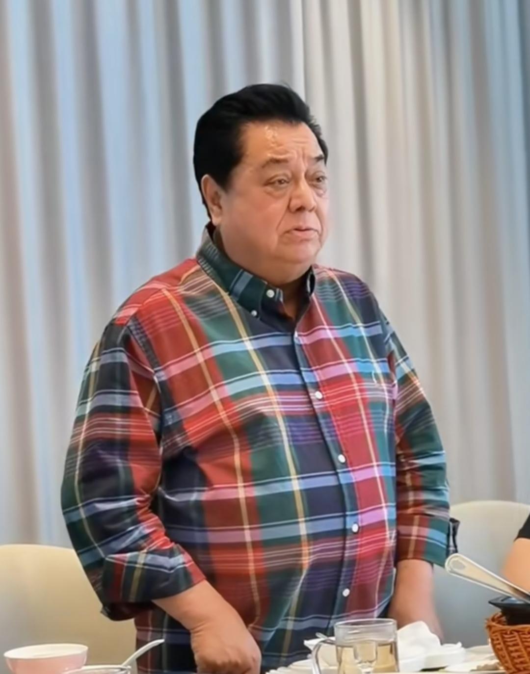 这位大叔穿着格子衬衫，站在桌边。很像一位演员啊，看着很面熟，多年没见了，他们那个