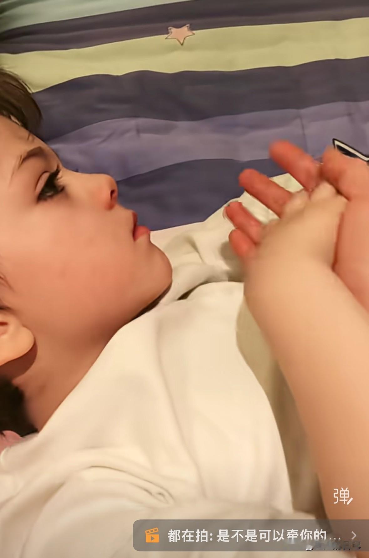 小宝的保姆周阿姨坐在床上，小宝躺在她的腿上，小周尝试把手伸过去，小宝自然的跟她我