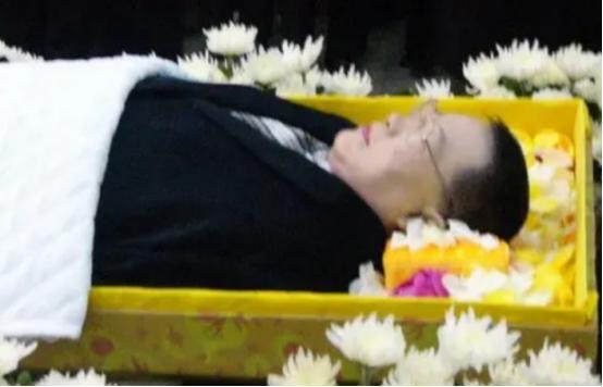 2004年，48岁的演员牛振华因车祸去世。镜头下他身着西装，安详地躺在鲜花丛中。