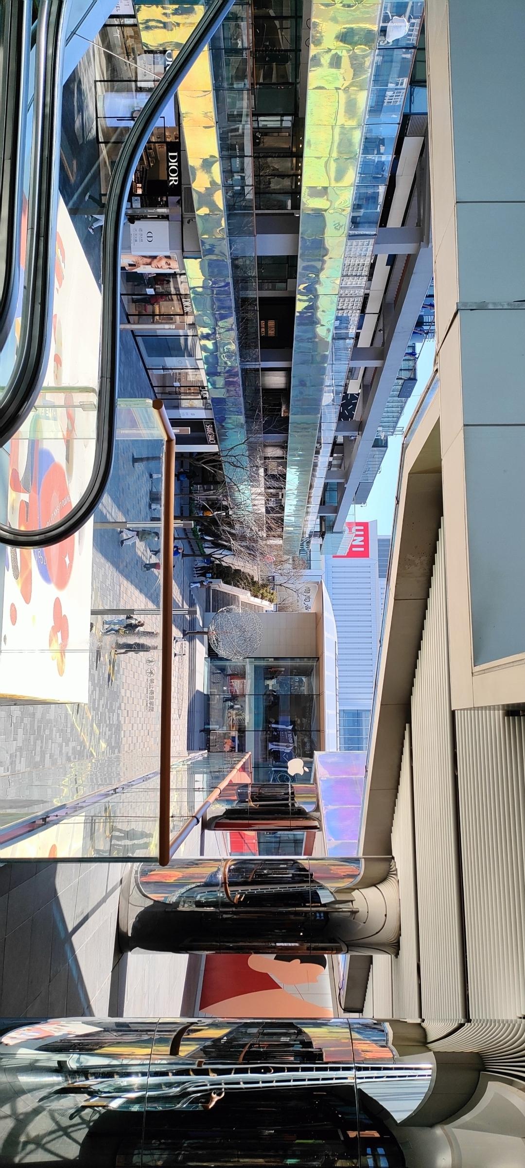现代都市的繁华与科技感，玻璃幕墙与自动扶梯交相辉映，购物天堂的魅力尽显。