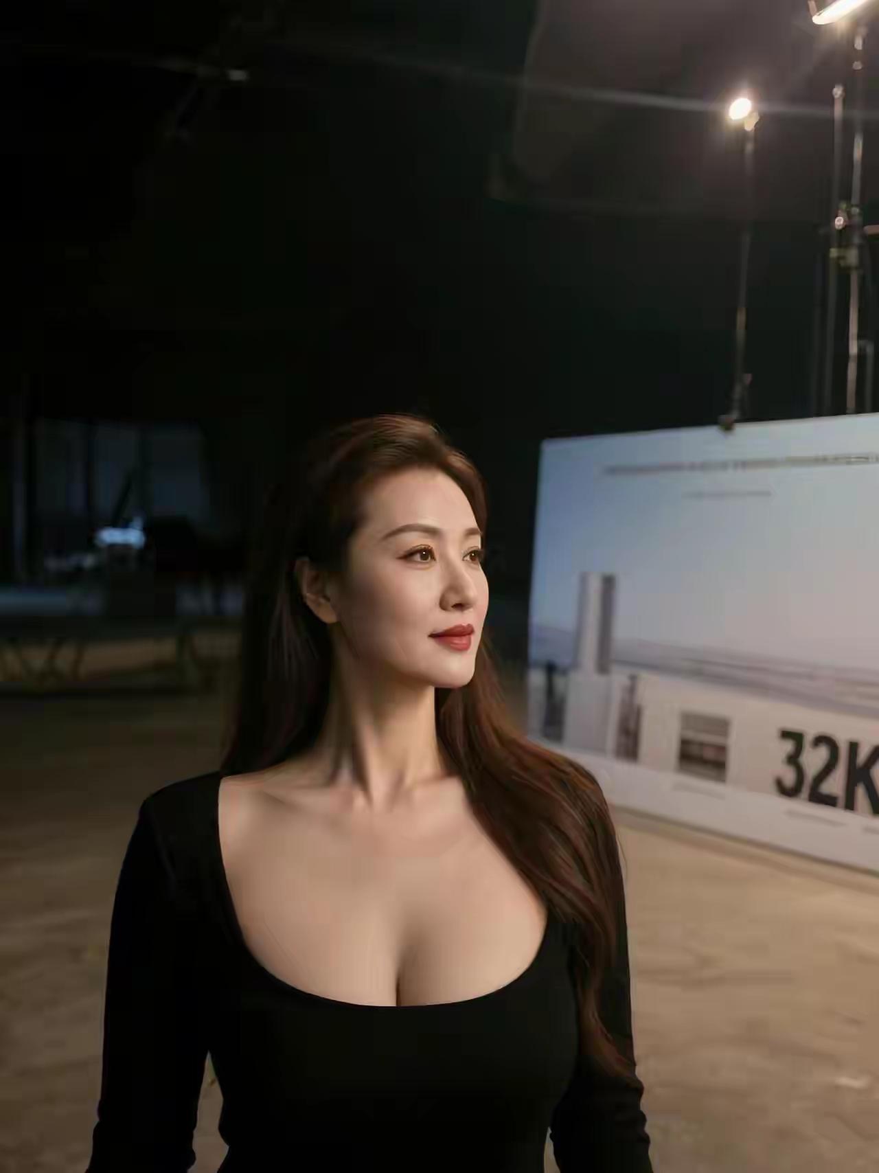 她如星芒璀璨，乌发垂肩尽显优雅，红唇点绛似绽春芳。低领黑裳勾勒曼妙曲线，颈间线条