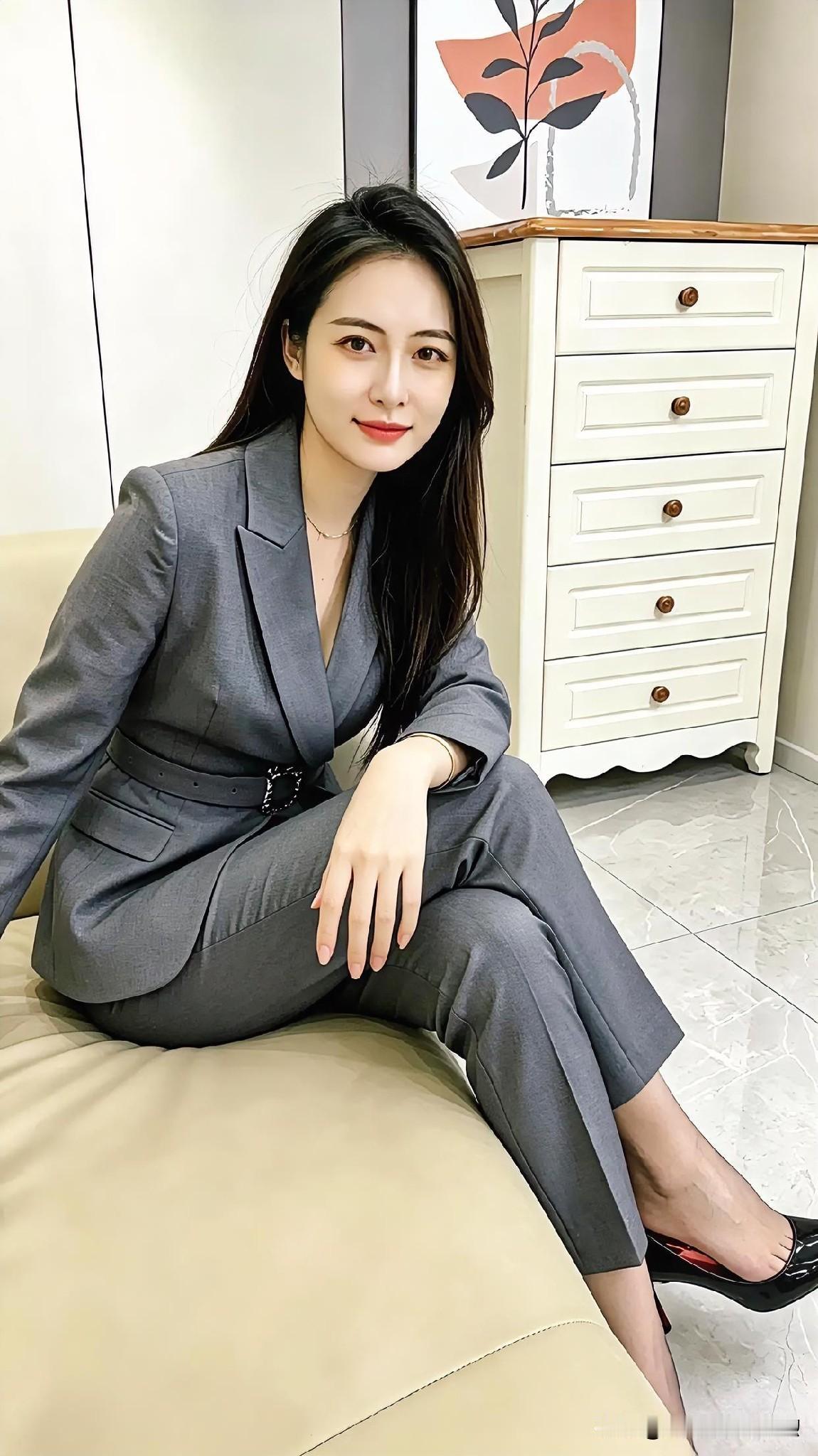 灰色西装套装，室内柔和光影。坐姿舒展，于简约中彰显干练与温婉气质。