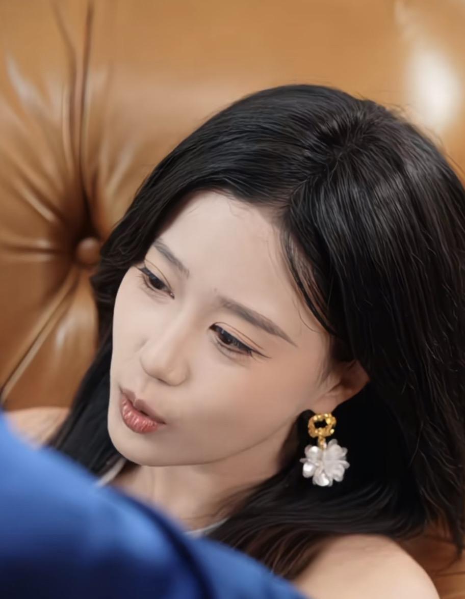 这位美女正坐在沙发上，看着手机。