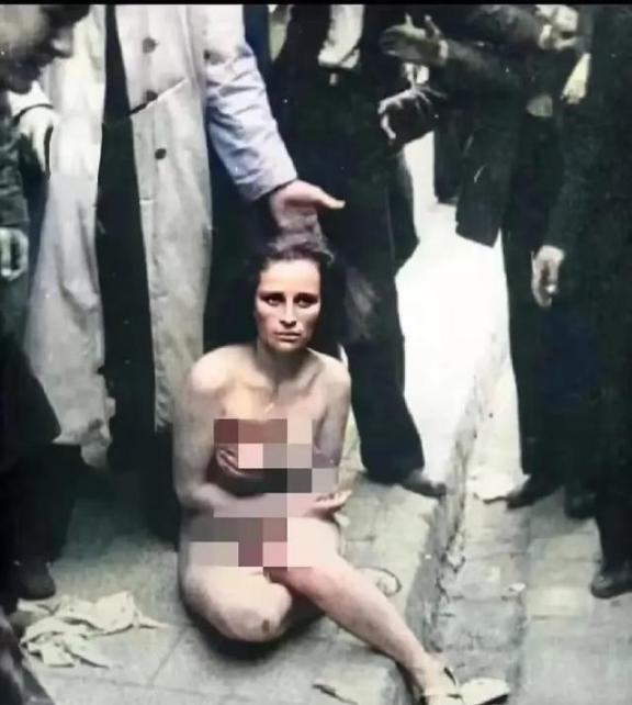 1941年，乌克兰利沃夫市，一名犹太女子被脱光了衣服，坐在那里忍受着众人的围观。