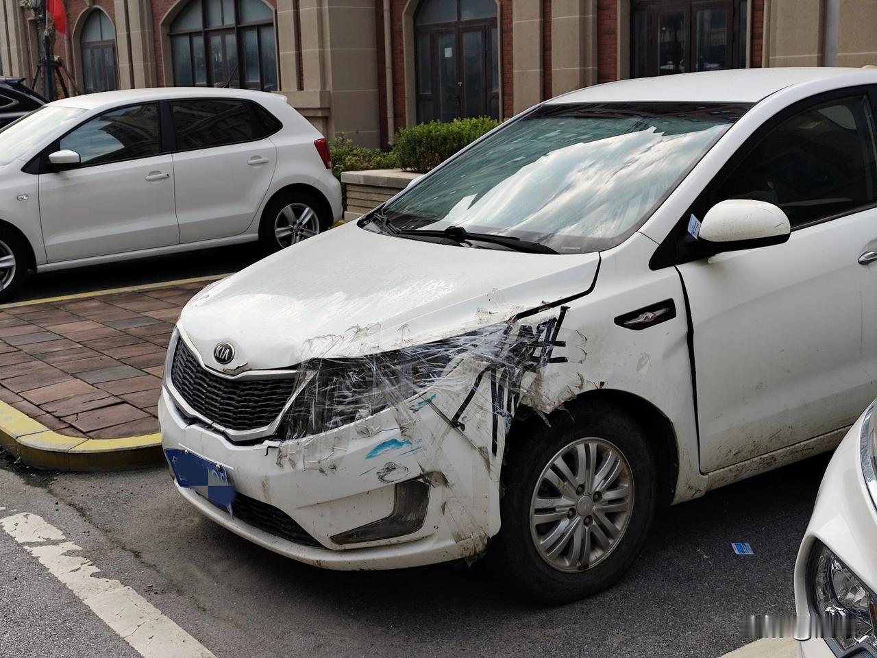 小区里停车位上一辆轿车，保险杠已经完全脱落，车主人没有急着去维修而是用胶带把它五