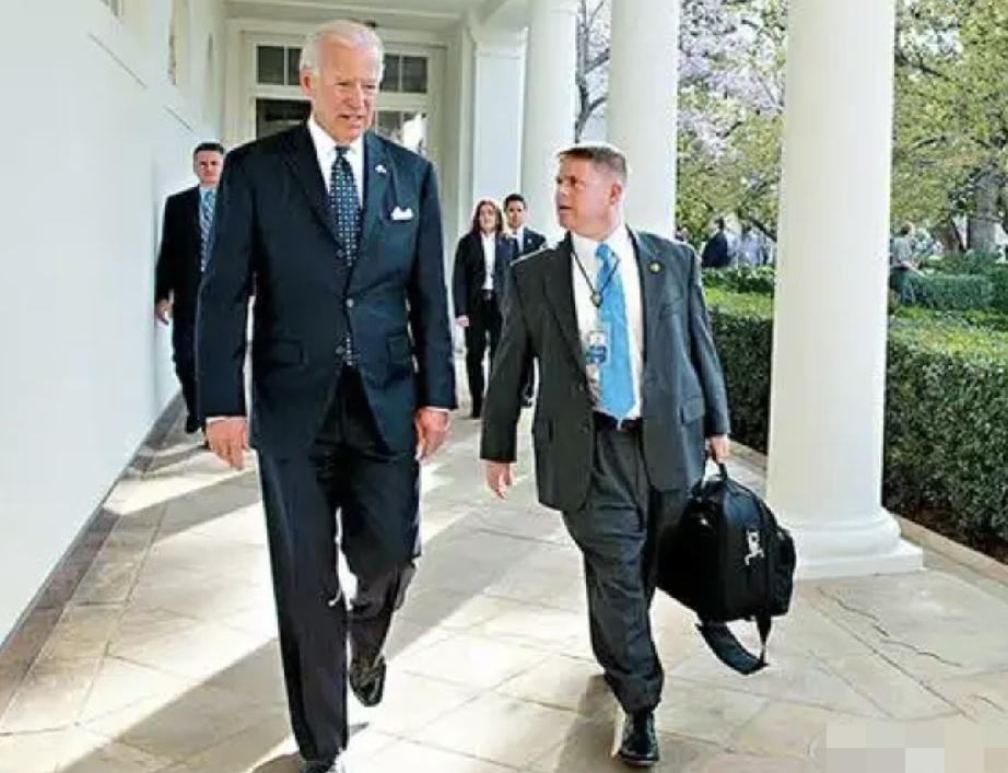拜登和一个拿着大提包的男子同行，他的个子比提包男的高很多；
手拿易拉罐的拜登头发