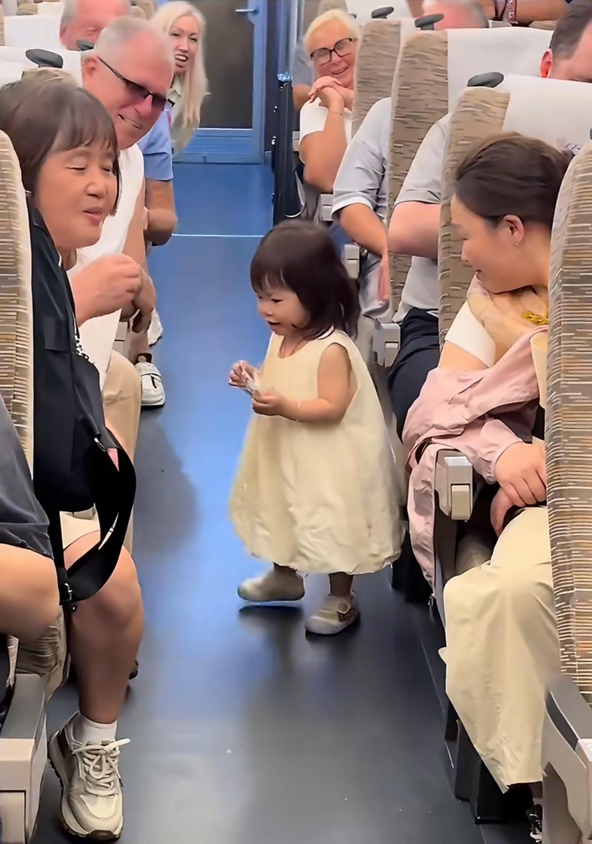 全车都是姨母笑，中国小女孩与外国游客分享零食，大家纷纷看着小孩子的纯真行为，所有