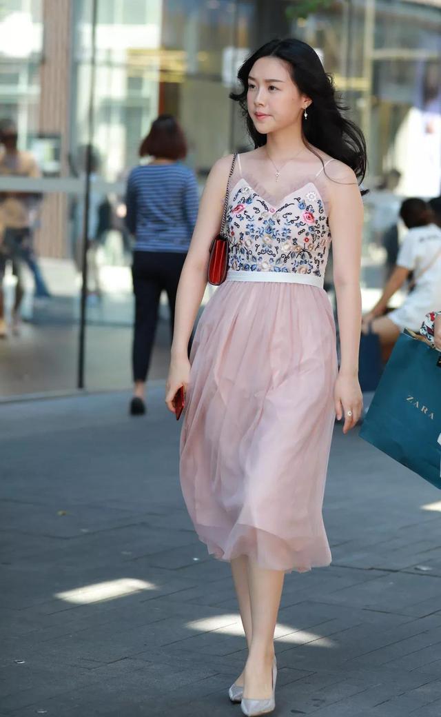 优雅漫步在都市街头，粉色裙摆随风飘扬，ZARA手袋相伴，时尚与自信并存。