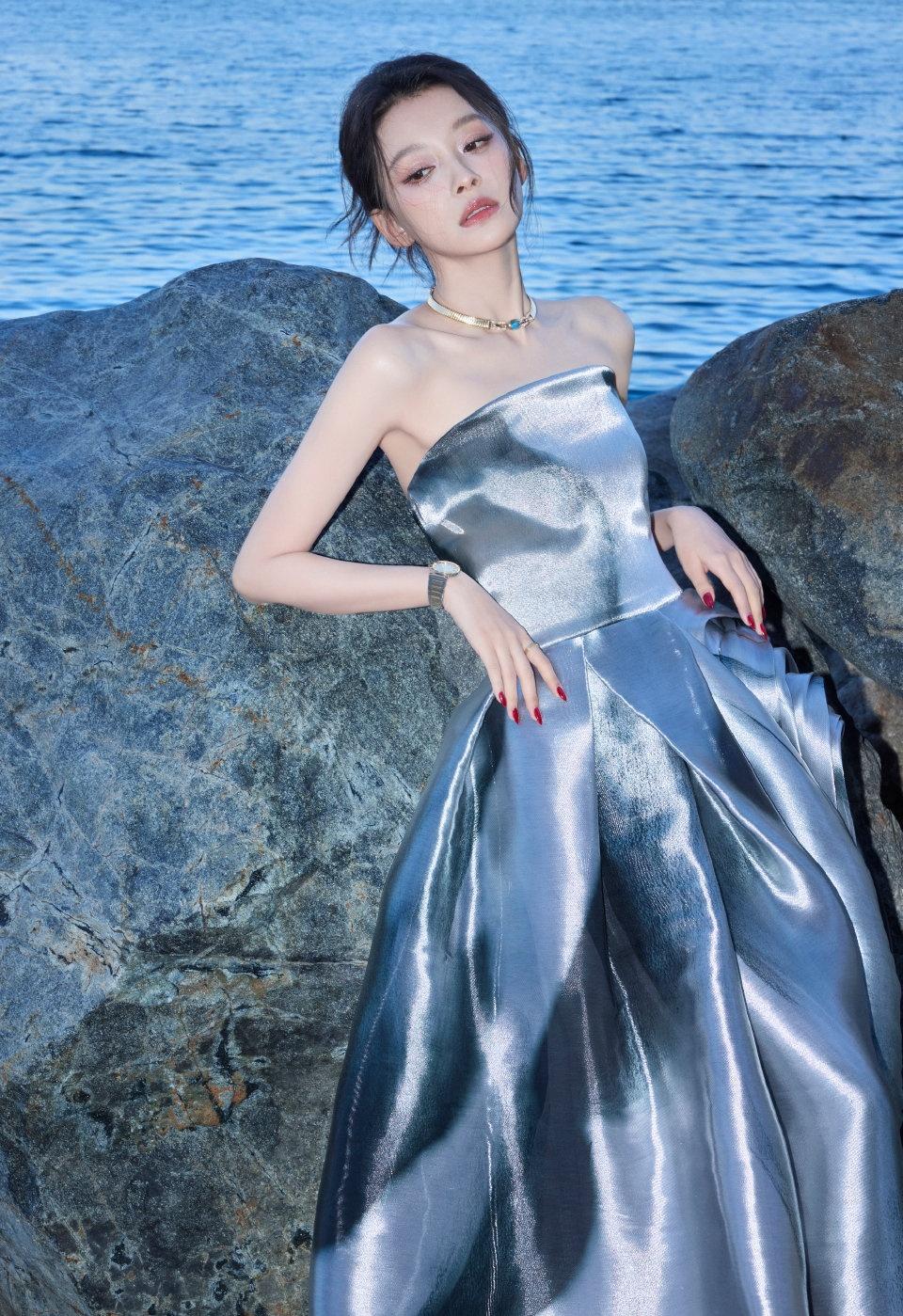 孙怡身着银色抹胸缎面长裙漫步海边，裙摆如海浪般灵动轻盈，与背景融合，美得自然。