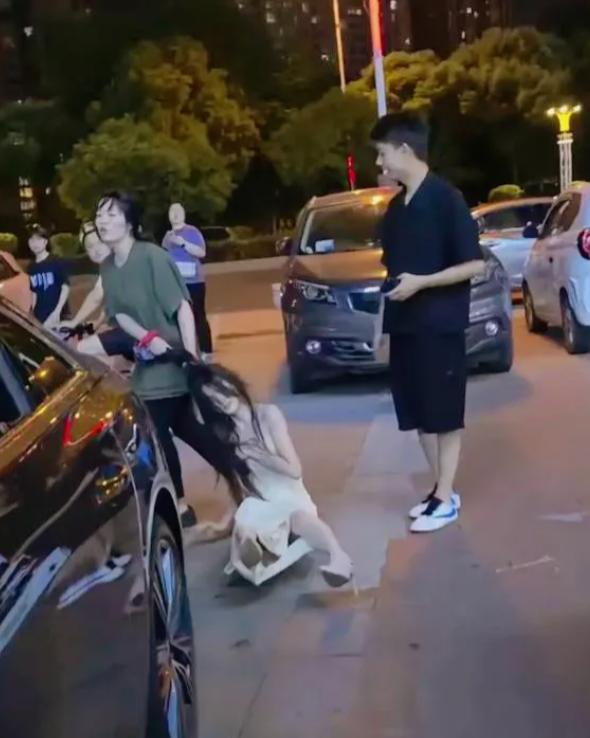 街头这一幕，看得人心里五味杂陈。
 
夜晚的马路上，绿衣女子死死拽住白衣女子的头