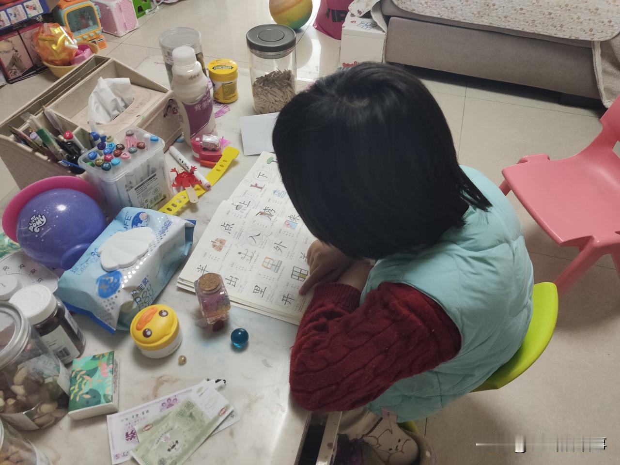 小家伙一大早就自己穿衣服起来，洗脸刷牙后，自己找出识字书本默读起来，看样子这是想