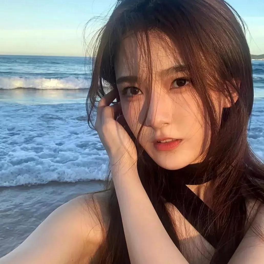 海风吹拂下的夏日海滩，少女轻轻抚摸着脸庞，温柔如画。海边活力少女 海边度假少女 